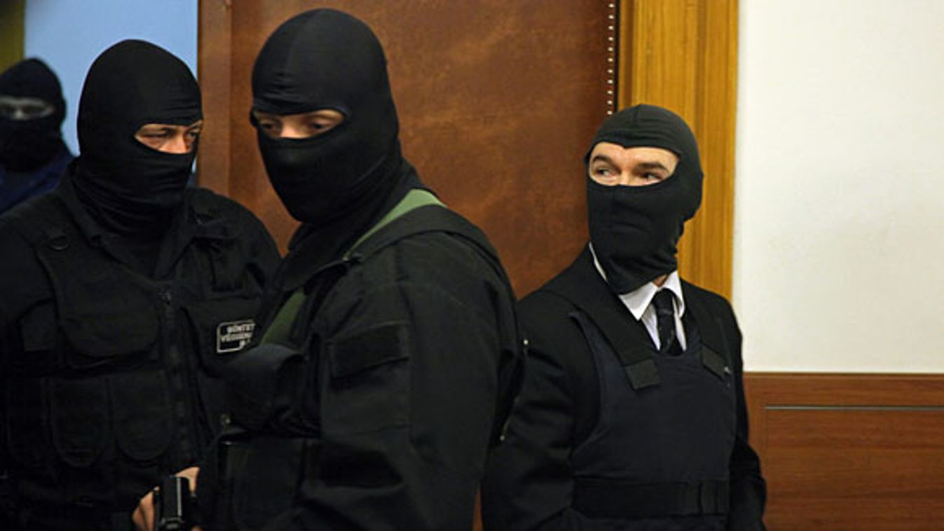 A büntetés-végrehajtás géppisztolyos kommandósai kísérik be a Fővárosi Bíróság tárgyalótermébe a golyóálló mellényt és maszkot viselő Jozef Rohácot (jobbra)
