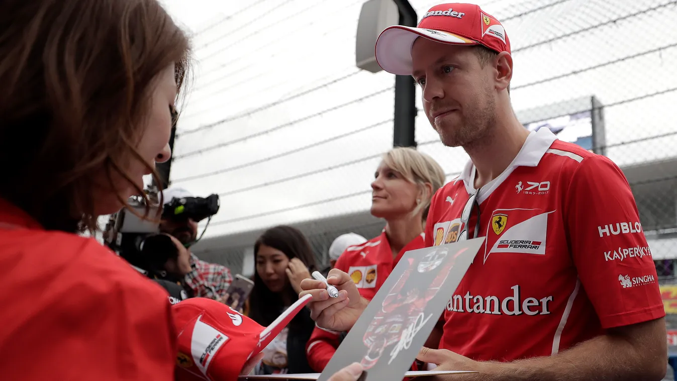 auto-prix Horizontal Ferrari's German driver Sebastian Vettel (R) signs an autograph for a fan during the Formula One Japanese Grand Prix at Suzuka circuit on October 5, 2017. / AFP PHOTO / Kiyoshi OTA 