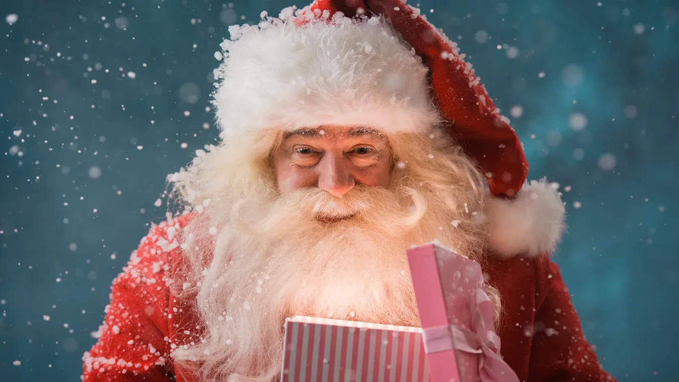 Happy Santa Claus opening his Christmas gift at North Pole Holiday Portrait Males Blinking Miracle Celebration Facial Expression Snowing Pole Smiley Face Lighting Equipment North Pole Smiling Looking Opening Santa Claus Fun Cap Hat One Person Joy Surprise