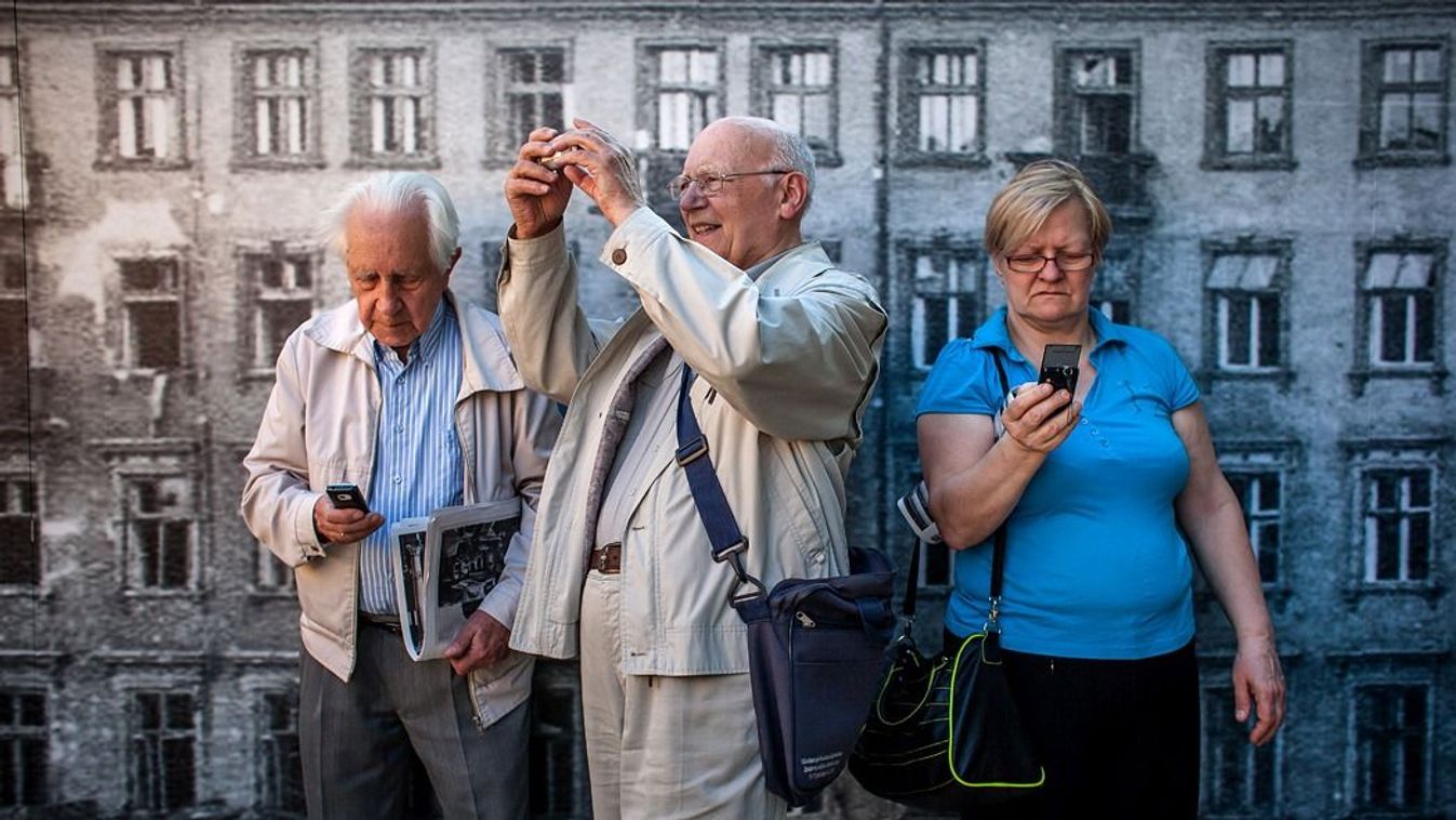 Nyugdíjas óriások. Látogatók a második világháborúban Varsóban létrehozott gettó és a Nagyzsinagóga 1:10 méretű modelljeit fényképezik a lengyel fővárosban