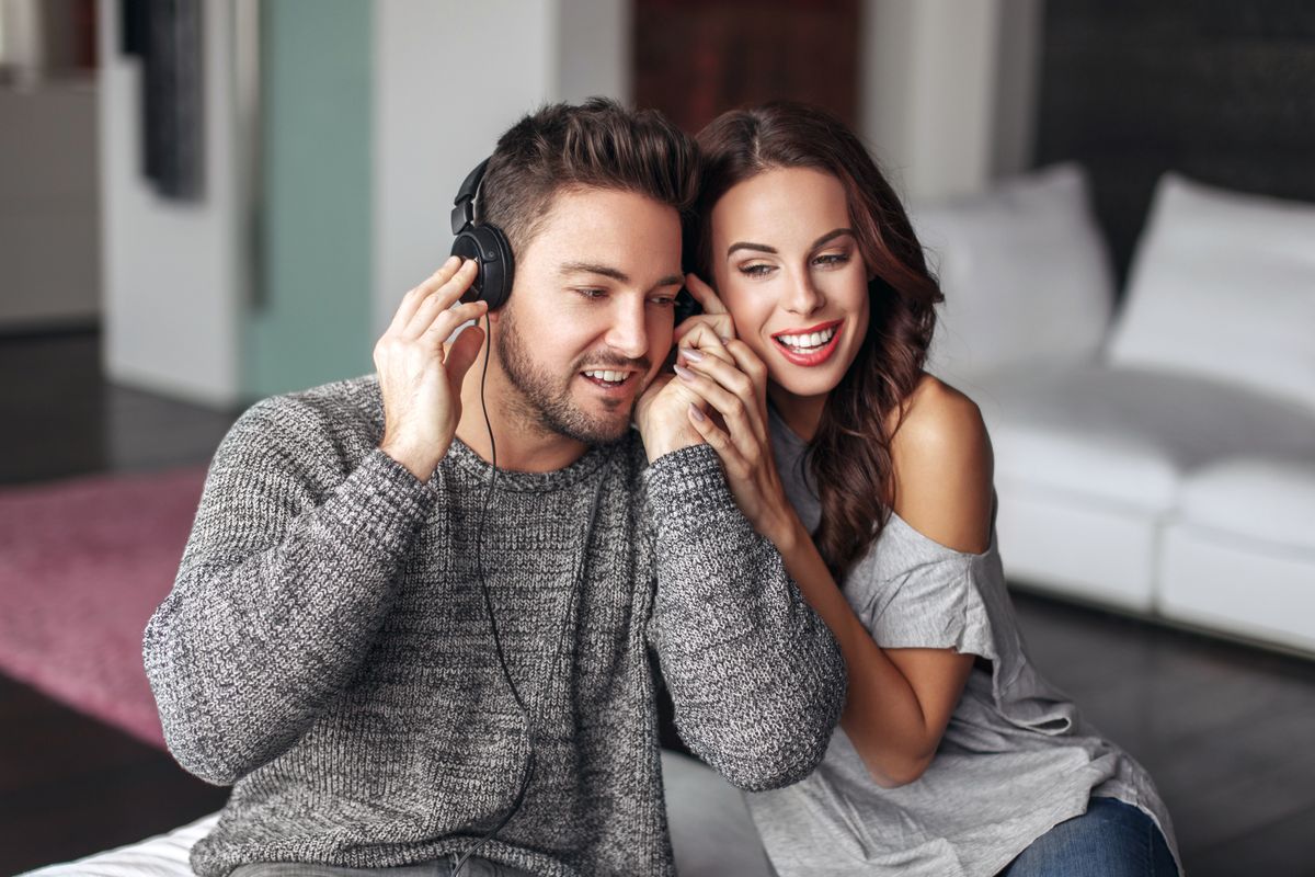 Happy,Young,Couple,Listening,Music,And,At,Home,,Sharing,Headphones