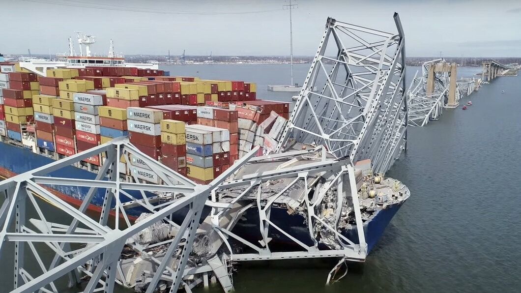 Az amerikai Országos Közlekedésbiztonsági Hivatal (NTSB) videójáról készített képen a baltimore-i Francis Scott Key híd acélszerkezetének roncsai alá szorulva vesztegel a Dali konténerszállító hajó 2024. március 27-én.