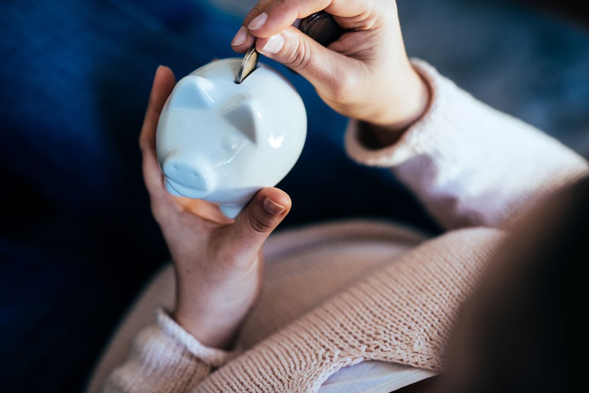 Woman adding a coin to savings in a piggy bank.