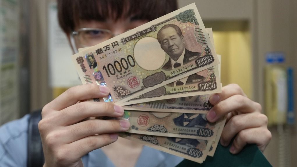 Egy férfi mutatja a bankautomatából felvett új japán bankjegyeket Szaitamában 2024. július 3-án, a bemutatásuk napján.