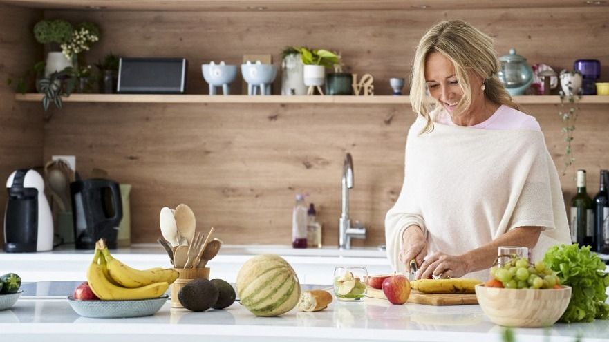 Attratctive middle age woman cutting fruit in her kitchen