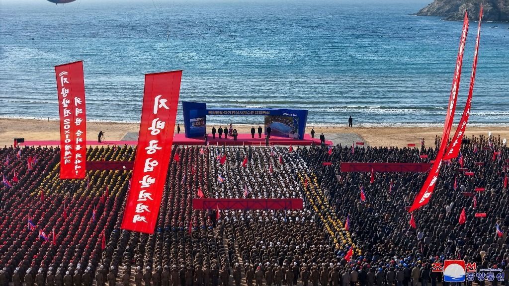 Az eseményen Kim Dzsongun több száz építőmunkáshoz szólt, akik egységes formációkban álltak, színes védősisakjaik látványos mintázatot alkottak a tömegben