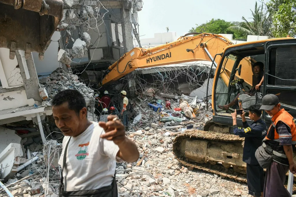 Heavy construction equipment is used to dig through the rubble as people look for survivors in a damaged building in Mandalay on March 29, 2025, a day after an earthquake struck central Myanmar. Rescuers dug through the rubble of collapsed buildings on March 29 in a desperate search for survivors after a huge earthquake hit Myanmar and Thailand, killing more than 1000 people. (Photo by Sai Aung MAIN / AFP)