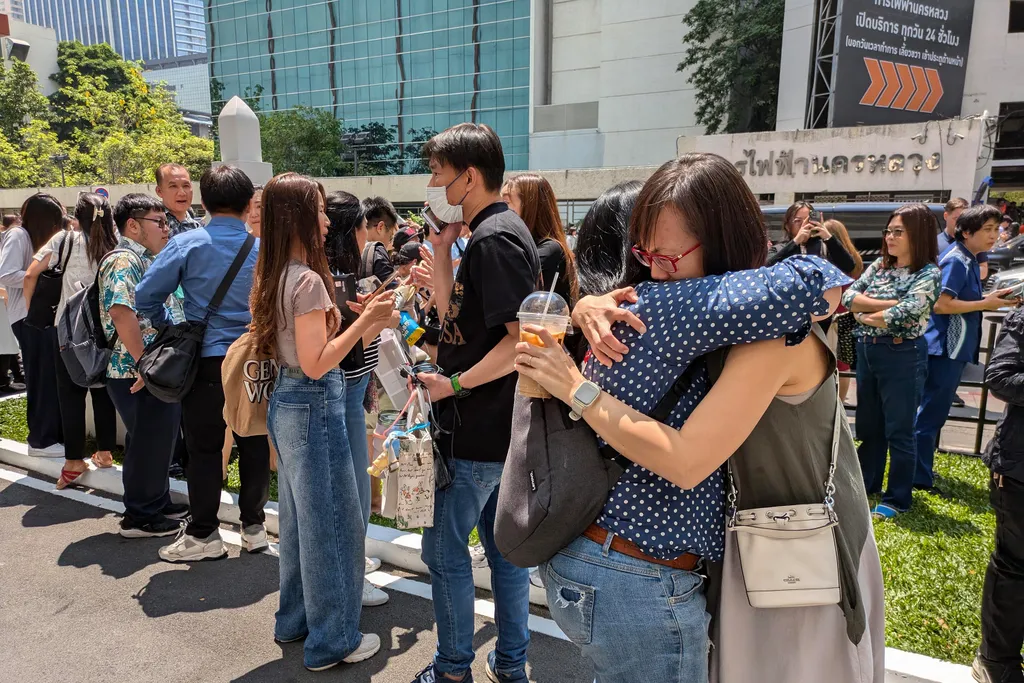 People stand outside an office building in Bangkok on March 28, 2025 after an earthquake. A powerful 7.7 magnitude earthquake hit central Myanmar on March 28, with tremors felt south into Thailand, with residents in the capital Bangkok runing into the str