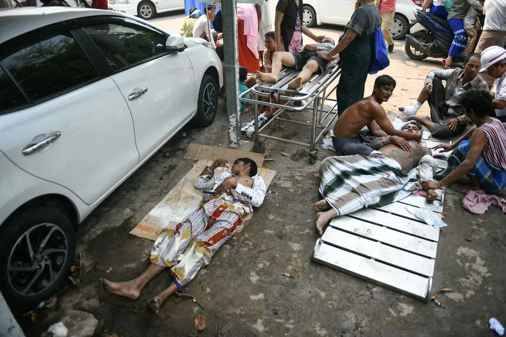 Survivors wait to receive medical attention as they lie on the ground of the compound of a hospital in Naypyidaw on March 28, 2025, after an earthquake in central Myanmar. A powerful earthquake rocked central Myanmar on March 28, buckling roads in capital