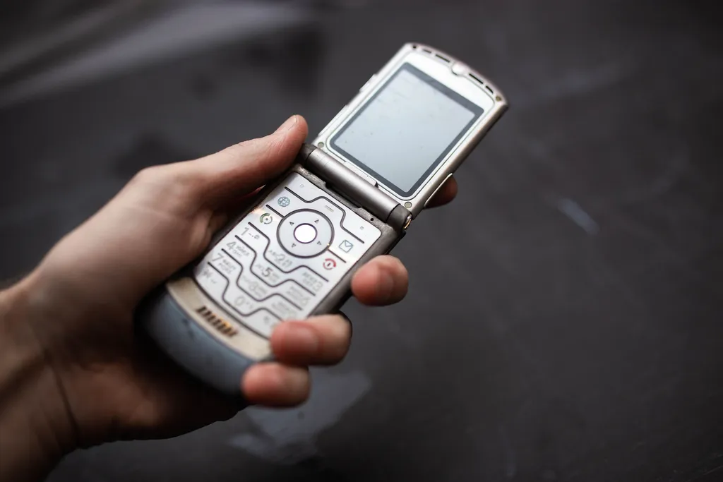 Minsk, Belarus - November 21, 2019: phone is held in hands against a dark background, Motorola RAZR V3, the slim flagship phone of 2004.