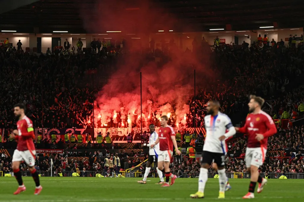 Lyon fans light up their flares during the UEFA Europa league quarter-final final, second leg football match between Manchester United and Lyon at Old Trafford stadium in Manchester, north west England, on April 17, 2025. (Photo by Oli SCARFF / AFP)