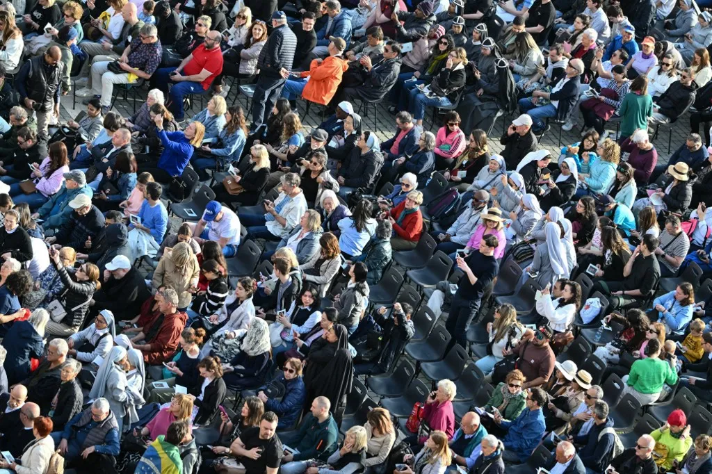 Attendees sit at St Peter's Square prior to the arrival of the coffin of Pope Francis, set to be transported from the chapel of Santa Marta to St Peter's Basilica, following the Pope's death, in the Vatican on April 23, 2025. The Pope died of a stroke, the Vatican announced hours after the death on April 21, 2025, of the 88-year-old reformer who inspired devotion but riled traditionalists during 12 years leading the Catholic Church. (Photo by Alberto PIZZOLI / AFP)
