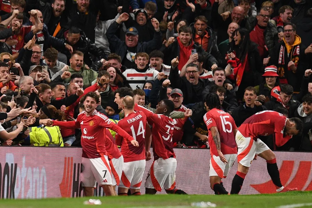 Manchester United's English defender #05 Harry Maguire (C) and teammates celebrate with their fans after Maguire scores their fifth goal during the UEFA Europa league quarter-final final, second leg football match between Manchester United and Lyon at Old Trafford stadium in Manchester, north west England, on April 17, 2025. (Photo by Oli SCARFF / AFP)