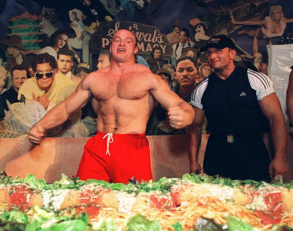 Ketrec, Mariusz Pudzianowski (L), prepares to dig in to the world's longest lasagna at Planet Hollywood in Hong Kong 12 October 1999. (Photo by IRA CHAPLAIN / AFP)