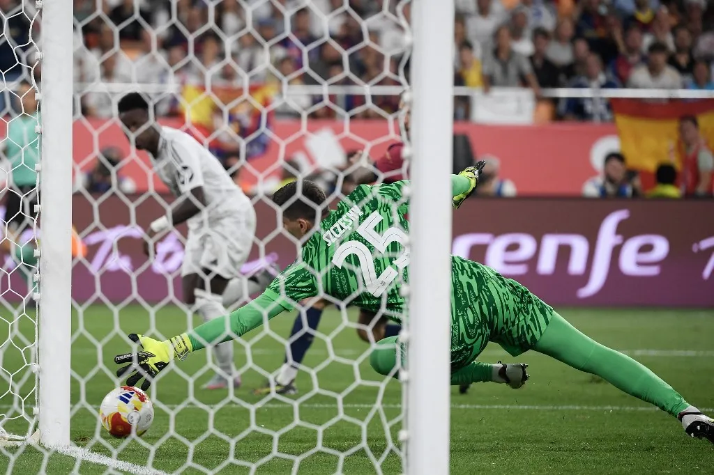 Barcelona's Polish goalkeeper #25 Wojciech Szczesny dives to save Real Madrid's Brazilian forward #07 Vinicius Junior's shot that strikes the post during their Spanish Cup, Copa del Rey (King's Cup) final football match between FC Barcelona and Real Madrid CF at La Cartuja stadium in Seville on April 26, 2025. (Photo by Josep LAGO / AFP)