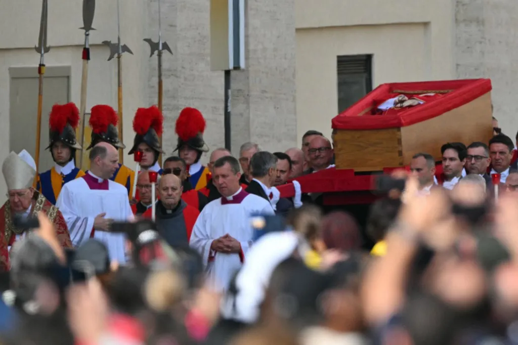 Pallbearers, next to Swiss Guards, carry the coffin (Top R) of the late Pope as it is transported from the chapel of Santa Marta to St Peter's Basilica, following the Pope's death, in the Vatican on April 23, 2025. The Pope died of a stroke, the Vatican announced hours after the death on April 21, 2025, of the 88-year-old reformer who inspired devotion but riled traditionalists during 12 years leading the Catholic Church. (Photo by Andreas SOLARO / AFP)