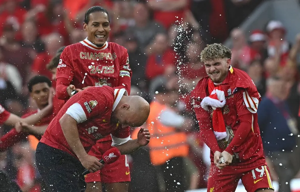 Liverpool's Dutch manager Arne Slot reacts as Liverpool's Dutch defender #04 Virgil van Dijk (L) and Liverpool's English midfielder #19 Harvey Elliott spray him with champagne after the English Premier League football match between Liverpool and Tottenham Hotspur at Anfield in Liverpool, north west England on April 27, 2025. Liverpool won the match 5-1, making them the winners of the Premier League title. (Photo by Paul ELLIS / AFP) / RESTRICTED TO EDITORIAL USE. No use with unauthorized audio, video, data, fixture lists, club/league logos or 'live' services. Online in-match use limited to 120 images. An additional 40 images may be used in extra time. No video emulation. Social media in-match use limited to 120 images. An additional 40 images may be used in extra time. No use in betting publications, games or single club/league/player publications. /