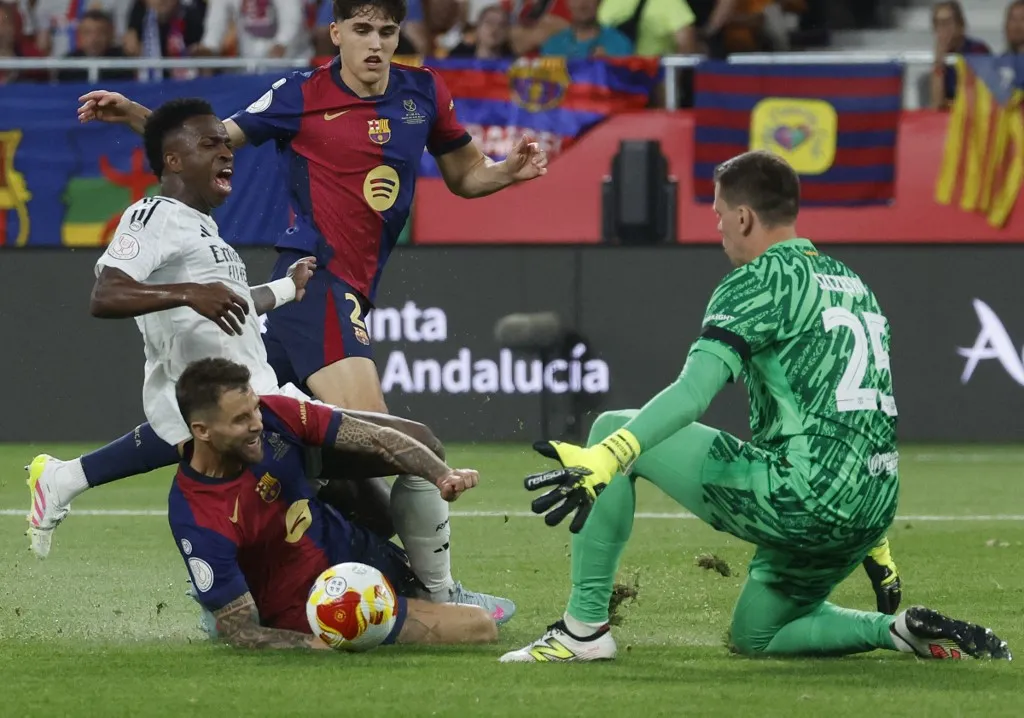 Barcelona's Spanish defender #05 Inigo Martinez Berridi (BOOTOM) fouls Real Madrid's Brazilian forward #07 Vinicius Junior during their Spanish Cup, Copa del Rey (King's Cup) final football match between FC Barcelona and Real Madrid CF at La Cartuja stadium in Seville on April 26, 2025. (Photo by Pierre-Philippe MARCOU / AFP)