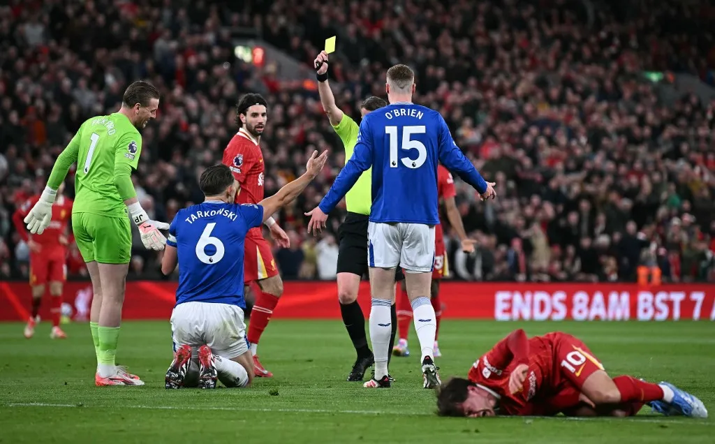Referee Sam Barrott shows a yellow card to Everton's English defender #06 James Tarkowski for a foul on Liverpool's Argentinian midfielder #10 Alexis Mac Allister during the English Premier League football match between Liverpool and Everton at Anfield in Liverpool, north west England on April 2, 2025. (Photo by Paul ELLIS / AFP) / RESTRICTED TO EDITORIAL USE. No use with unauthorized audio, video, data, fixture lists, club/league logos or 'live' services. Online in-match use limited to 120 images. An additional 40 images may be used in extra time. No video emulation. Social media in-match use limited to 120 images. An additional 40 images may be used in extra time. No use in betting publications, games or single club/league/player publications. /