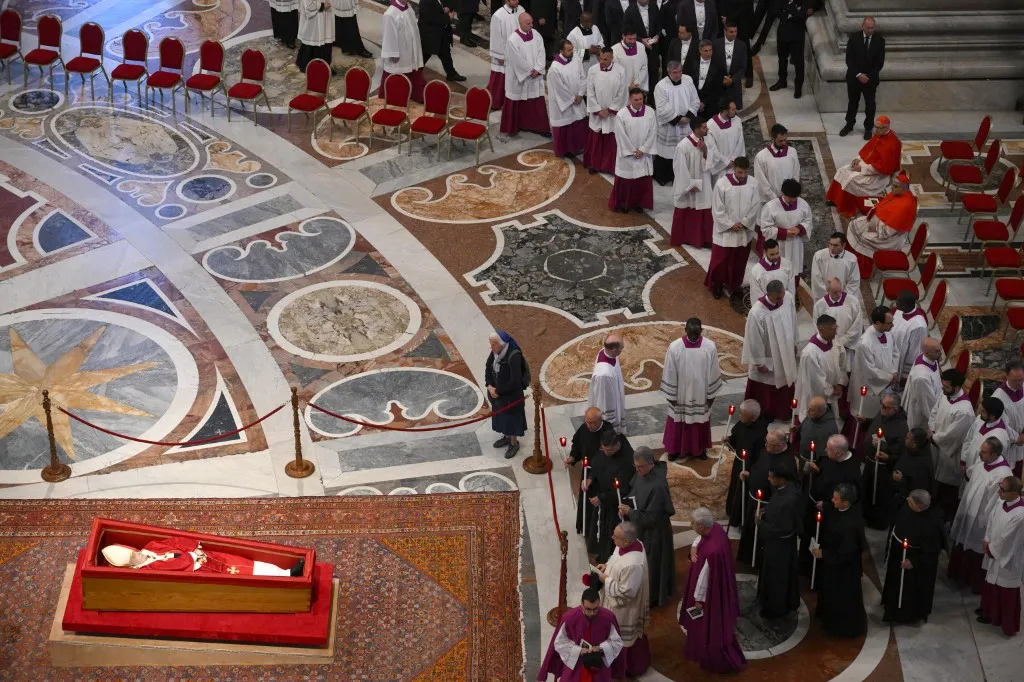 This photograph shows Pope Francis' coffin (Bottom L) as he lies in state with French nun Genevieve Jeanningros (C) paying her respects during a ceremony inside St Peter's Basilica following the procession of the late Pope's coffin from the chapel of Santa Marta to St Peter's Basilica, in the Vatican on April 23, 2025. The Pope died of a stroke, the Vatican announced hours after the death on April 21, 2025, of the 88-year-old reformer who inspired devotion but riled traditionalists during 12 years leading the Catholic Church. (Photo by Alessandro DI MEO / POOL / AFP)