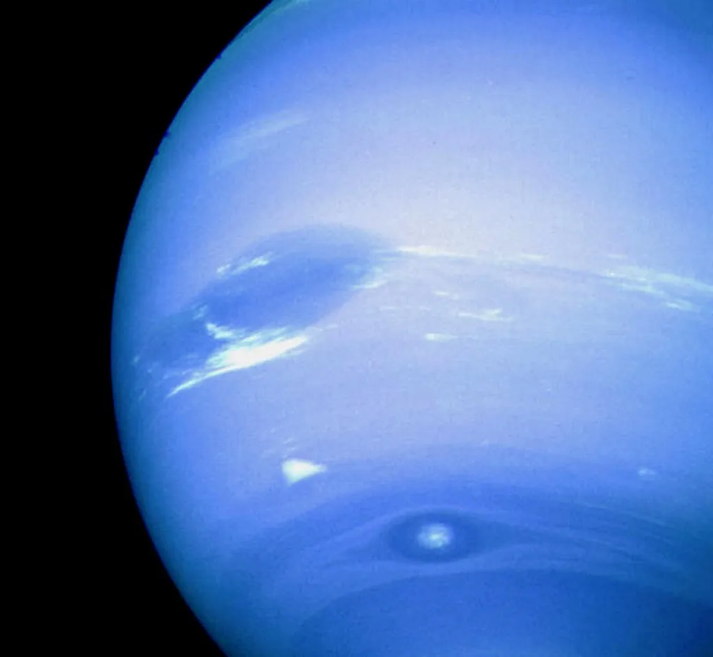 This NASA Voyager 2 image released 21 August, 2001 shows that the planet Neptune has spots. The Solar System's outermost gas giant shows a nearly uniform blue hue created by small amounts of methane drifting in a thick atmosphere of nearly colorless hydrogen and helium. Dark spots do appear, however, that are anti-cyclones: large high-pressure systems that swirl in Neptune's cold cloud tops. Two dark spots are visible in the above picture taken by the Voyager 2 spacecraft in 1989: an Earth-sized Great Dark Spot located on the far left, and Dark Spot 2 located near bottom. A bright cloud dubbed Scooter accompanies the Great Dark Spot. Subsequent images of Neptune by the Hubble Space Telescope in 1994 indicated that both of these dark spots had dissipated, but another had been created.  AFP PHOTO (Photo by NASA / NASA / AFP)