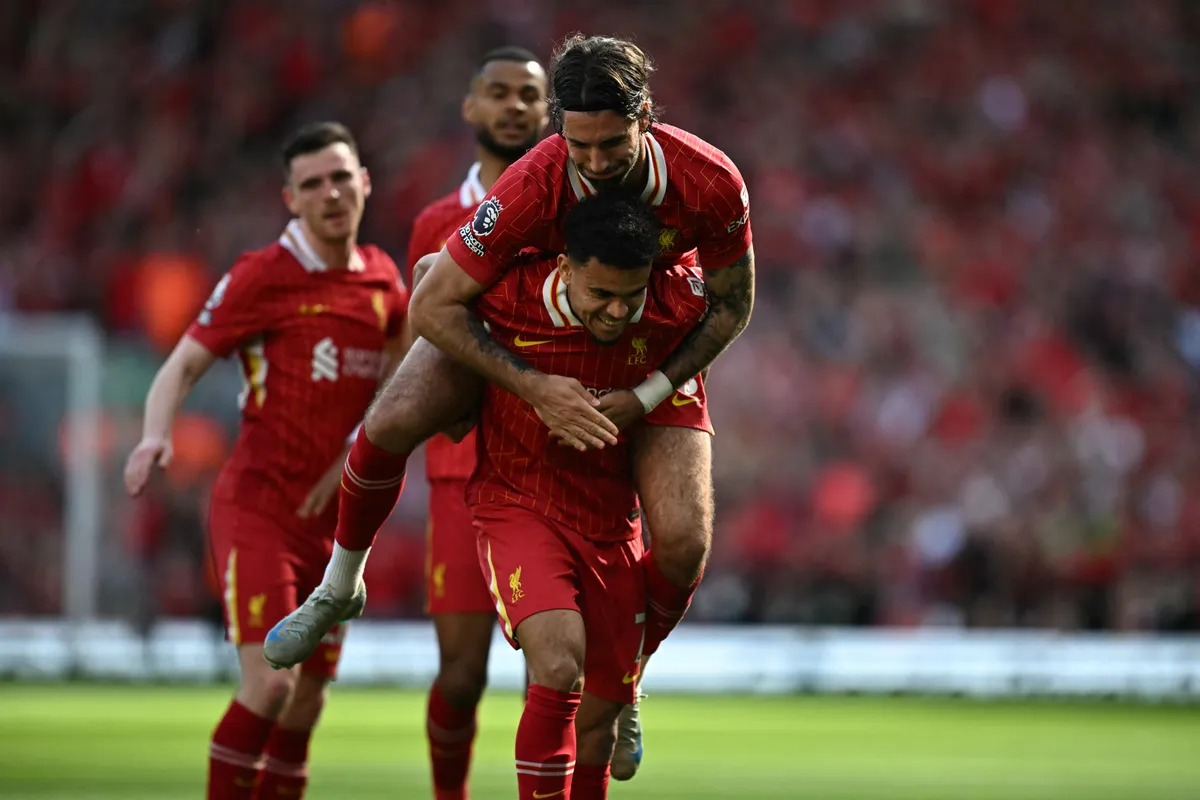 Liverpool's Hungarian midfielder #08 Dominik Szoboszlai leaps onto the back of Liverpool's Colombian midfielder #07 Luis Diaz as they celebrate combining for their first goal during the English Premier League football match between Liverpool and Tottenham Hotspur at Anfield in Liverpool, north west England on April 27, 2025. (Photo by Paul ELLIS / AFP) / RESTRICTED TO EDITORIAL USE. No use with unauthorized audio, video, data, fixture lists, club/league logos or 'live' services. Online in-match use limited to 120 images. An additional 40 images may be used in extra time. No video emulation. Social media in-match use limited to 120 images. An additional 40 images may be used in extra time. No use in betting publications, games or single club/league/player publications. /