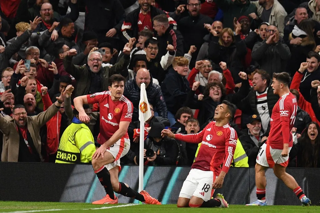 Manchester United's English defender #05 Harry Maguire (L) and teammates celebrate with their fans after Maguire scores their fifth goal during the UEFA Europa league quarter-final final, second leg football match between Manchester United and Lyon at Old Trafford stadium in Manchester, north west England, on April 17, 2025. (Photo by Oli SCARFF / AFP)