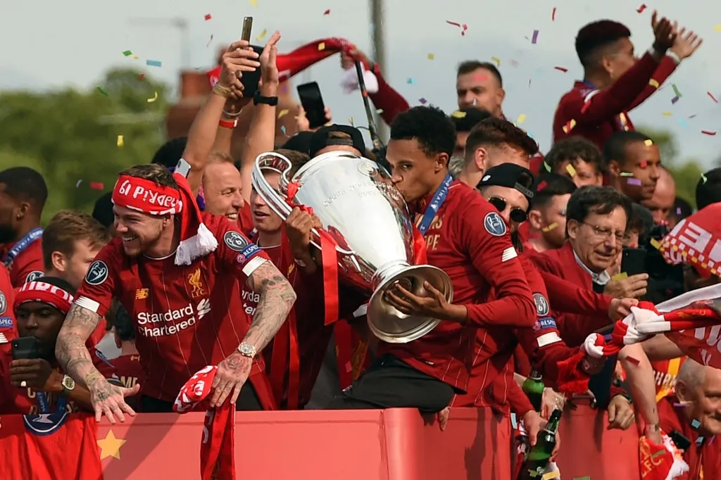 Liverpool's English defender Trent Alexander-Arnold kisses the European Champion Clubs' Cup trophy during an open-top bus parade around Liverpool, north-west England on June 2, 2019, after winning the UEFA Champions League final football match between Liverpool and Tottenham. Liverpool's celebrations stretched long into the night after they became six-time European champions with goals from Mohamed Salah and Divock Origi to beat Tottenham -- and the party was set to move to England on Sunday where tens of thousands of fans awaited the team's return. The 2-0 win in the sweltering Metropolitano Stadium delivered a first trophy in seven years for Liverpool, and -- finally -- a first win in seven finals for coach Jurgen Klopp. (Photo by Oli SCARFF / AFP)