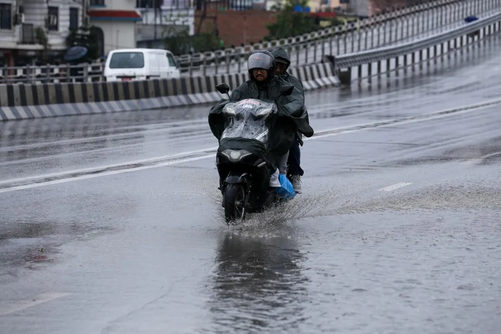 Motorcyclists drive along the highway in Kathmandu, Nepal, on May 4, 2025, wearing raincoats despite the heavy rainfall following the pre-monsoon climatic effect that takes form all across Nepal. The Weather Forecasting Division under the Department of Hydrology and Meteorology states that the country experiences the combined influence of westerly and local winds, along with a partial impact from moisture-laden air entering from the Bay of Bengal. The Division advises the public to take necessary precautions, as the expected weather conditions--rain, thunderstorms, and wind--may affect daily life, agriculture, health, as well as road and air transport. (Photo by Subaas Shrestha/NurPhoto) (Photo by Subaas Shrestha / NurPhoto / NurPhoto via AFP)