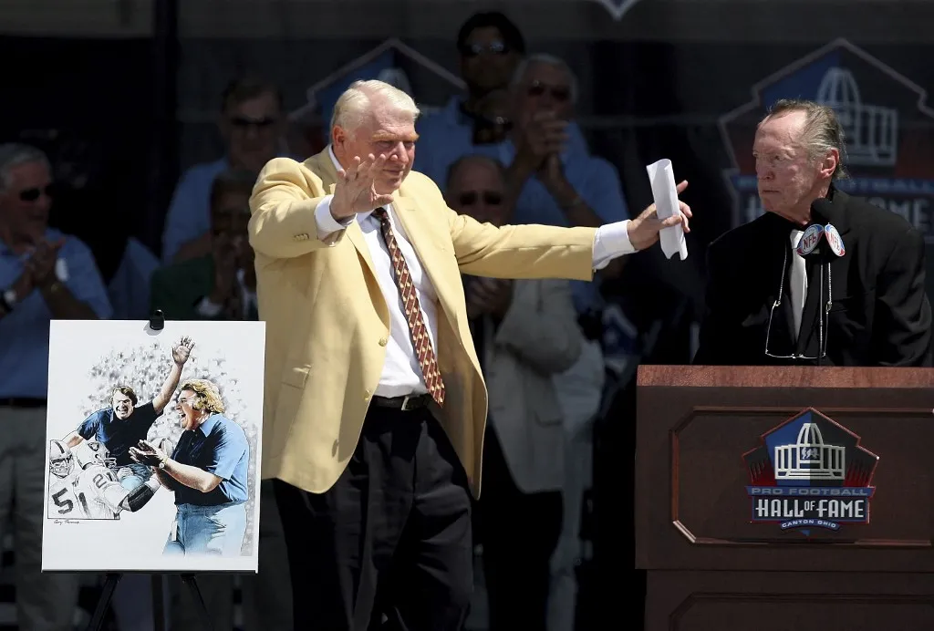 CANTON, OH - AUGUST 05:  Broadcaster and former coach Oakland Raider John Madden (L) gestures in front of a portrait of him after being introduced by Oakland Raider owner Al Davis during his induction during the Class of 2006 Pro Football Hall of Fame Enshrinement Ceremony at Fawcett Stadium on August 5, 2006 in Canton, Ohio.  (Photo by Doug Benc/Getty Images) *** Local Caption *** John Madden;Al Davis (Photo by Doug Benc / Getty Images North America / Getty Images via AFP)