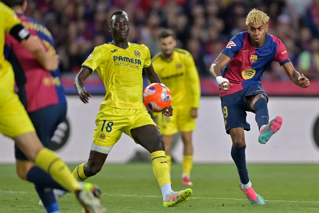 Barcelona's Spanish forward #19 Lamine Yamal takes a shot while marked by Villarreal's Senegalese midfielder #18 Pape Gueye during the Spanish league football match between FC Barcelona and Villarreal CF at Estadi Olimpic Lluis Companys in Barcelona on May 18, 2025. (Photo by MANAURE QUINTERO / AFP)