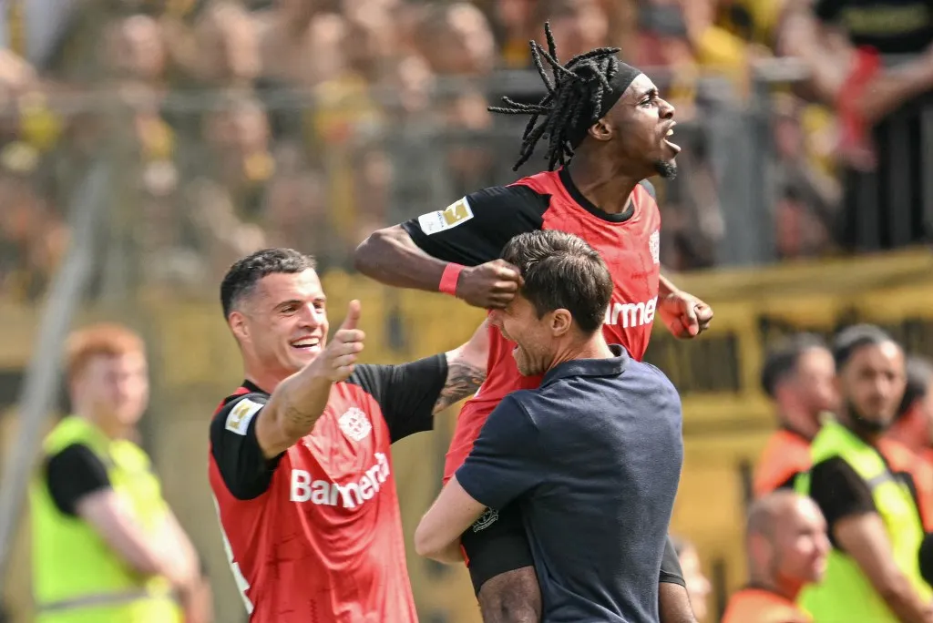 Bayer Leverkusen's Dutch defender #30 Jeremie Frimpong celebrates his 1-0 with Bayer Leverkusen's Spanish head coach Xabi Alonso and Bayer Leverkusen's Swiss midfielder #34 Granit Xhaka during the German first division Bundesliga football match between Bayer 04 Leverkusen and Borussia Dortmund in Leverkusen, western Germany, on May 11, 2025. (Photo by INA FASSBENDER / AFP) / DFL REGULATIONS PROHIBIT ANY USE OF PHOTOGRAPHS AS IMAGE SEQUENCES AND/OR QUASI-VIDEO