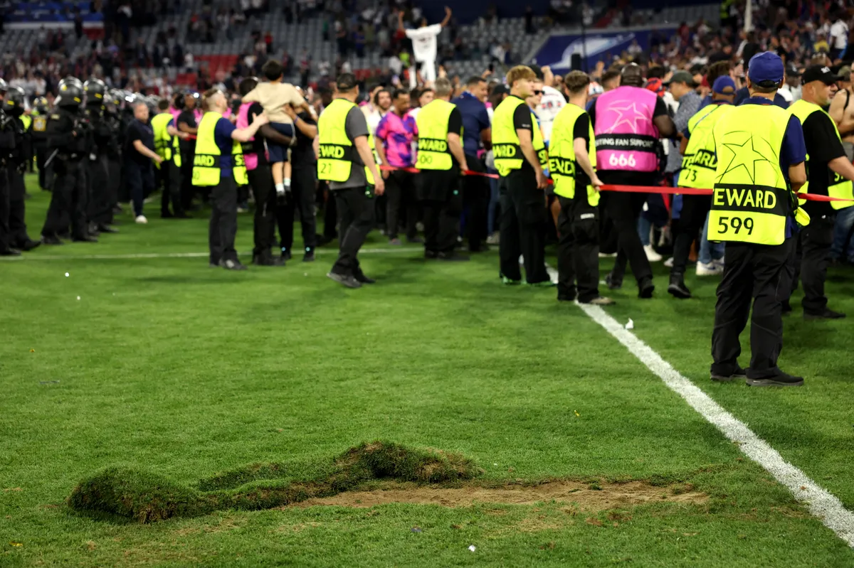 PSG, Stewards gather near grass torn off the pitch by PSG fans as a souvenir at the end of the UEFA Champions League final football match between Paris Saint-Germain (PSG) and Inter Milan in Munich, southern Germany on May 31, 2025. Paris Saint-Germain won the Champions League for the first time by thrashing Inter Milan 5-0 in the most one-sided final in the competition's history. (Photo by Odd ANDERSEN / AFP)