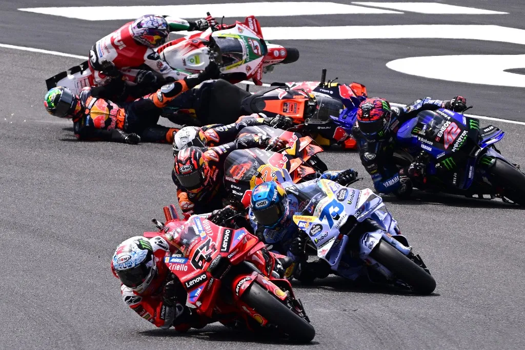 Forma-1 Ducati Lenovo Team's Italian MotoGP rider Francesco Bagnaia leads the pack as Red Bull KTM Factory Racing team's South African MotoGp rider Brad Binder (L) and LRC Honda team's French MotoGP rider Johann Zarco (up) crash during the sprint on the eve of the Italian Moto GP Grand Prix at Mugello circuit, in Mugello, near Florence, on June 21, 2025. (Photo by Tiziana FABI / AFP)