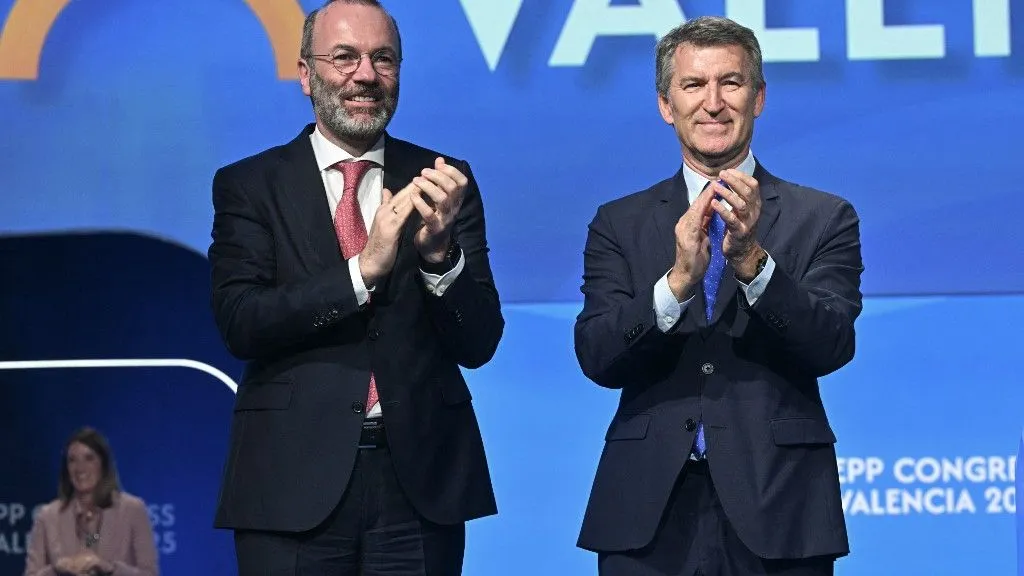 Spain's opposition Popular Party (PP) leader Alberto Nunez Feijoo (R) and President of the European People's Party (EPP) Manfred Weber applaud on stage at the European People's Party (EPP) congress in Valencia, on April 30, 2025. (Photo by JOSE JORDAN / AFP)