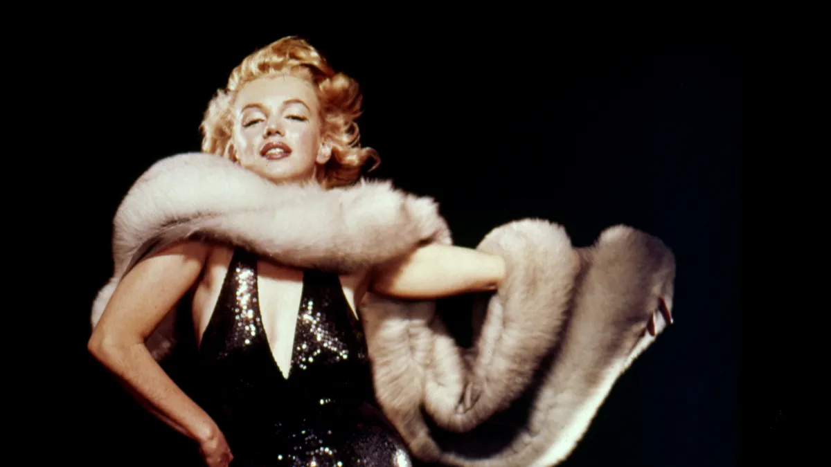 Circa 1956, Los Angeles, California, USA: American actress and Hollywood icon MARILYN MONROE poses in a low cut black sequin dress and long fur stole in this classic portrait.