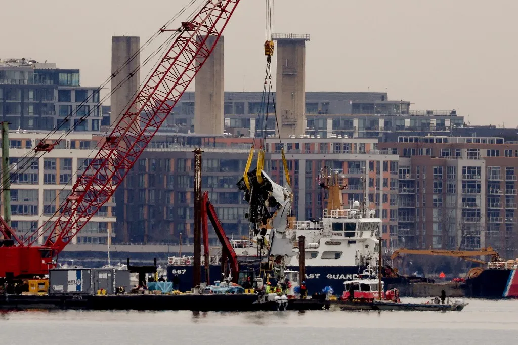 ARLINGTON, VIRGINIA - FEBRUARY 03: A large portion of the damaged plane fuselage is lifted from the Potomac River during recovery efforts after the American Airlines crash on February 03, 2025 in Arlington, Virginia. An American Airlines flight from Wichita, Kansas collided midair with a military Black Hawk helicopter while on approach to Ronald Reagan Washington National Airport on January 29, 2025 outside of Washington, DC. According to reports, there were no survivors among the 67 people onboard both aircraft.   Samuel Corum/Getty Images/AFP (Photo by Samuel Corum / GETTY IMAGES NORTH AMERICA / Getty Images via AFP)