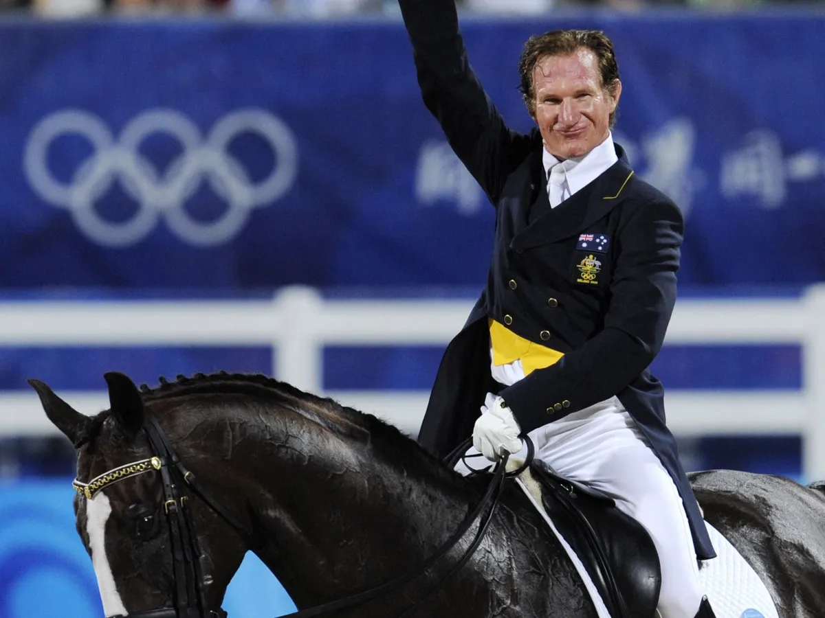 olimpikon Australias Heath Ryan waves after riding with "Greenoaks Dundee" during the 2008 Beijing Olympic Games Grand Prix Dressage Equestrian event on August 13, 2008 in Hong Kong. 47 Riders compete in the Dressage individual.     AFP PHOTO MIKE CLARKE (Photo by MIKE CLARKE / AFP)