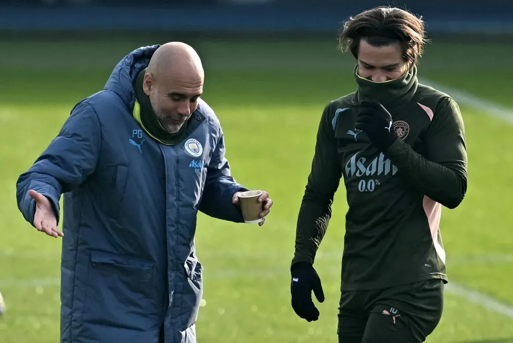 Manchester City's Spanish manager Pep Guardiola (L) jokes with Manchester City's English midfielder #10 Jack Grealish during a training session at Manchester City's training ground in Manchester, north-west England, on February 18, 2025, on the eve of their UEFA Champions League second-leg Knockout Round play-off football match against Real Madrid. (Photo by Paul ELLIS / AFP)