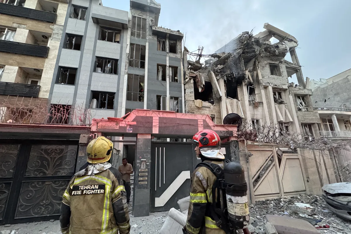 First-responders gather outside a building that was hit by an Israeli strike in Tehran on June 13, 2025. Israel hit about 100 targets in Iran on June 13, including nuclear facilities and military command centres and killing senior figures including the armed forces chief and top nuclear scientists. (Photo by MEGHDAD MADADI / TASNIM NEWS / AFP)