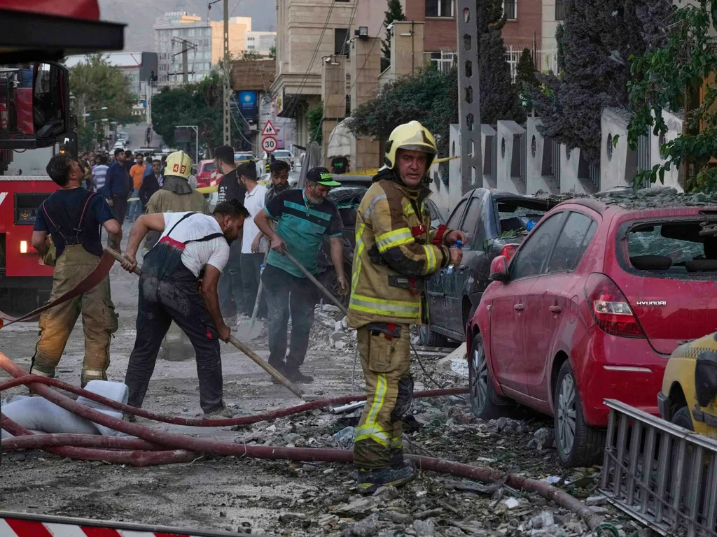Izrael, Irán, háború, Izrael légicsapás, zsidó állam, Teherán, fegyverkezés,  nukleáris fegyverkezés, 2025.06.11., IzraelIránháború Teherán, 2025. június 13.
Tűzoltó áll megrongálódott autók és épülettörmelékek mellett Teheránban 2025. június 13-án, az Ir