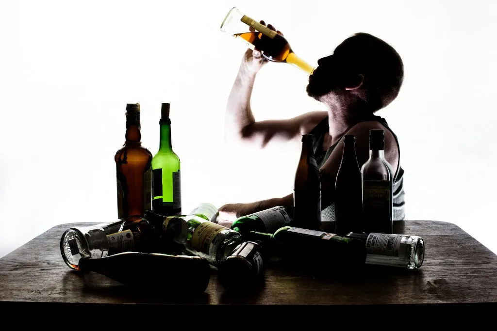 ILLUSTRATION - A man sits at a table with empty bottles of liquor, beer, champagne, and wine in Dresden (Saxony), Germany, 22 May 2015. Photo: Thomas Eisenhuth/dpa -NO WIRE SERVICE- (Photo by Thomas Eisenhuth / ZB / dpa Picture-Alliance via AFP)