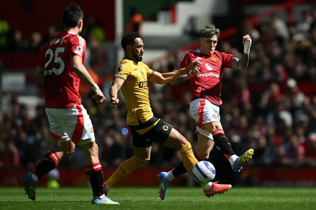Wolverhampton Wanderers' Brazilian striker #10 Matheus Cunha (C) vies with Manchester United 's Argentinian midfielder #17 Alejandro Garnacho (R) during the English Premier League football match between Manchester United and Wolverhampton Wanderers at Old Trafford in Manchester, north west England, on April 20, 2025. (Photo by Paul ELLIS / AFP) / RESTRICTED TO EDITORIAL USE. No use with unauthorized audio, video, data, fixture lists, club/league logos or 'live' services. Online in-match use limited to 120 images. An additional 40 images may be used in extra time. No video emulation. Social media in-match use limited to 120 images. An additional 40 images may be used in extra time. No use in betting publications, games or single club/league/player publications. / 