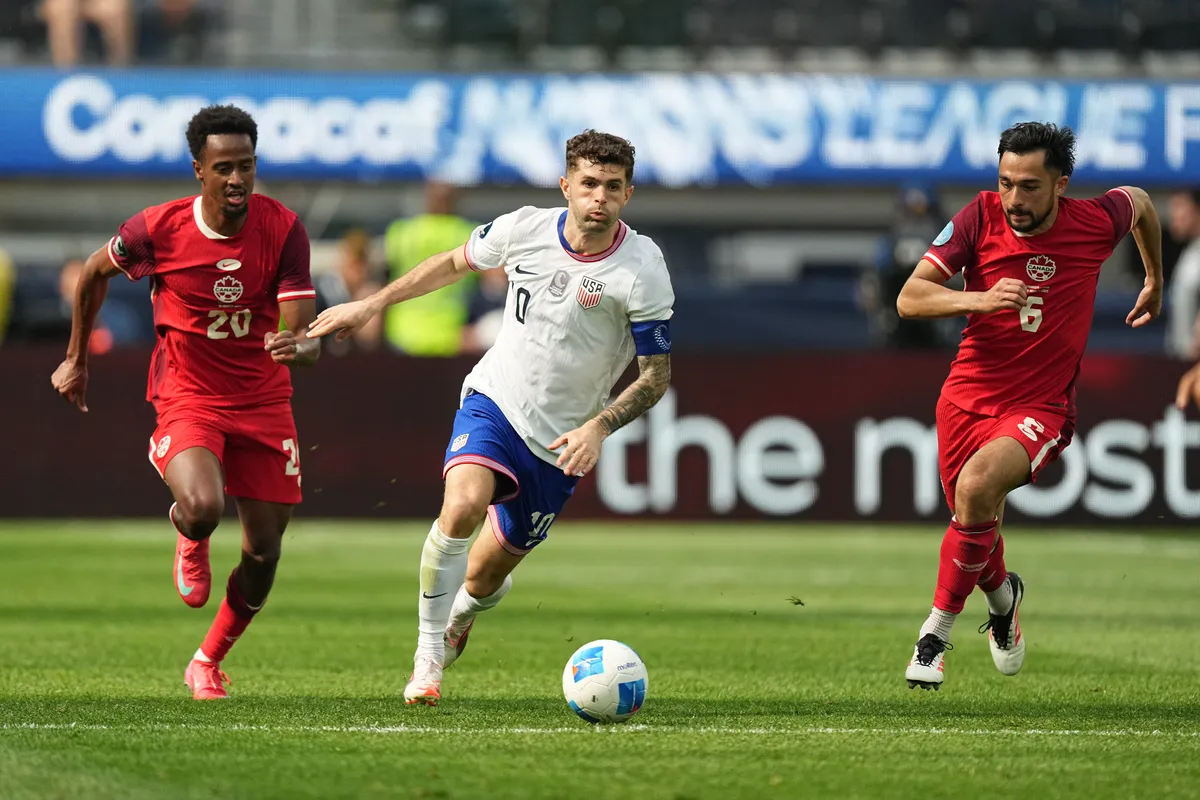 INGLEWOOD, CALIFORNIA - MARCH 23: Christian Pulisic #10 of the United States controls the ball against Ali Ahmed (L) #20 and Niko Sigur #6 of Canada during the first half of the CONCACAF Nations League third-place match at SoFi Stadium on March 23, 2025 in Inglewood, California.   Michael Owens/Getty Images/AFP (Photo by Michael Owens / GETTY IMAGES NORTH AMERICA / Getty Images via AFP)
