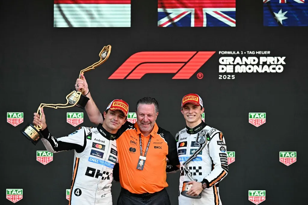 McLaren's British driver Lando Norris lifts his trophy in the air as he celebrates winning the Formula One Monaco Grand Prix on the podium with McLaren's CEO Zak Brown (C) and third-placed McLaren's Australian driver Oscar Piastri (R) at the Circuit de Monaco, on May 25, 2025. (Photo by Gabriel BOUYS / AFP)