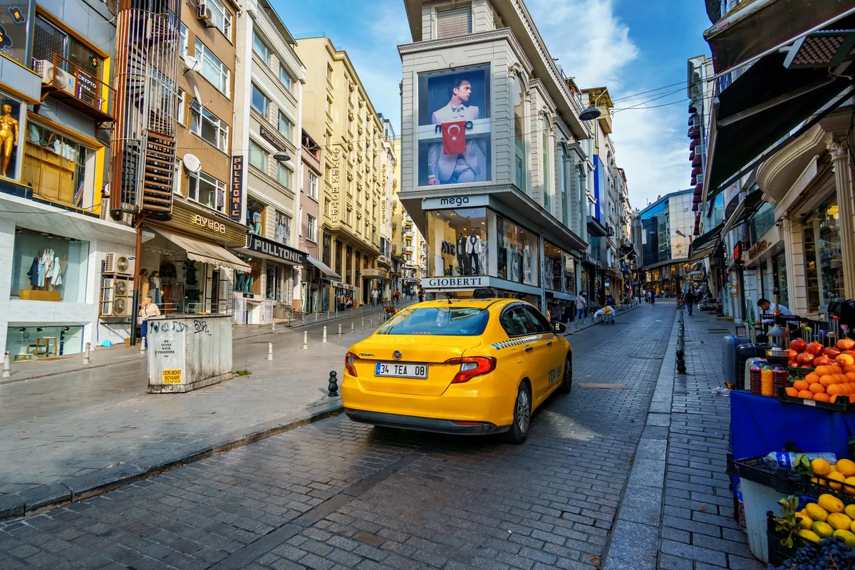 Istanbul, Turkey - October 11, 2024: yellow taxi, city life and street view, urban architecture, shops and advertising signs, random people