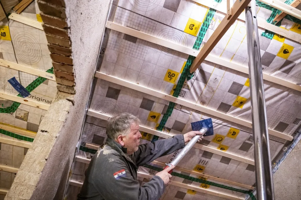 Man installing insulation in a ceiling framework in a construction setting. Netherlands (Photo by Pancake Pictures / Connect Images via AFP) szigetelés