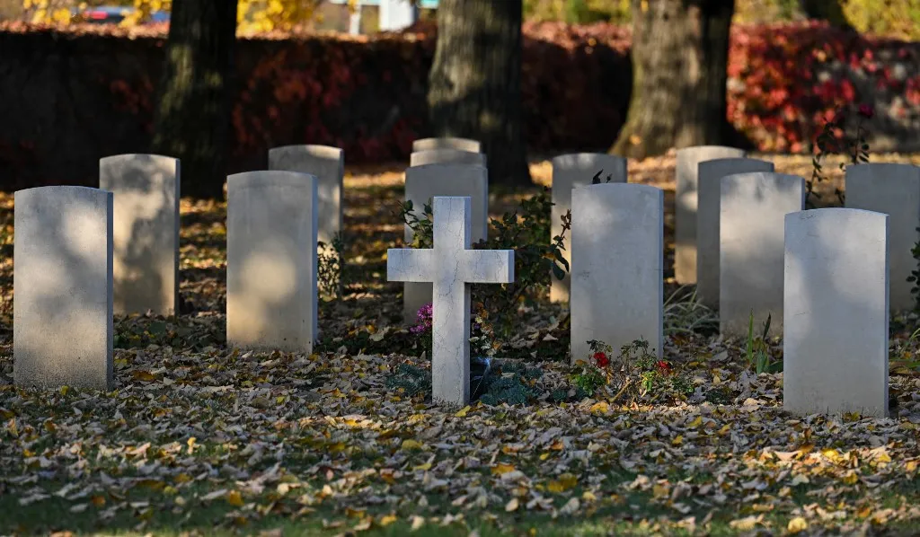 A cross for a French victim is seen between the headstones of British graves at the Budapest War Cemetery, close to Solymar, Hungary on October 30, 2024, ahead of the Day of the Dead. The cemetery contains one single First World War burial, and 173 Commonwealth burials of World War II, all of them airmen whose graves were brought in from sites all over Hungary after the war. Three of them are unidentified. The cemetery also contains one French and 37 Polish War Graves, according to the Commonwealth War Graves Commission. (Photo by ATTILA KISBENEDEK / AFP), halál