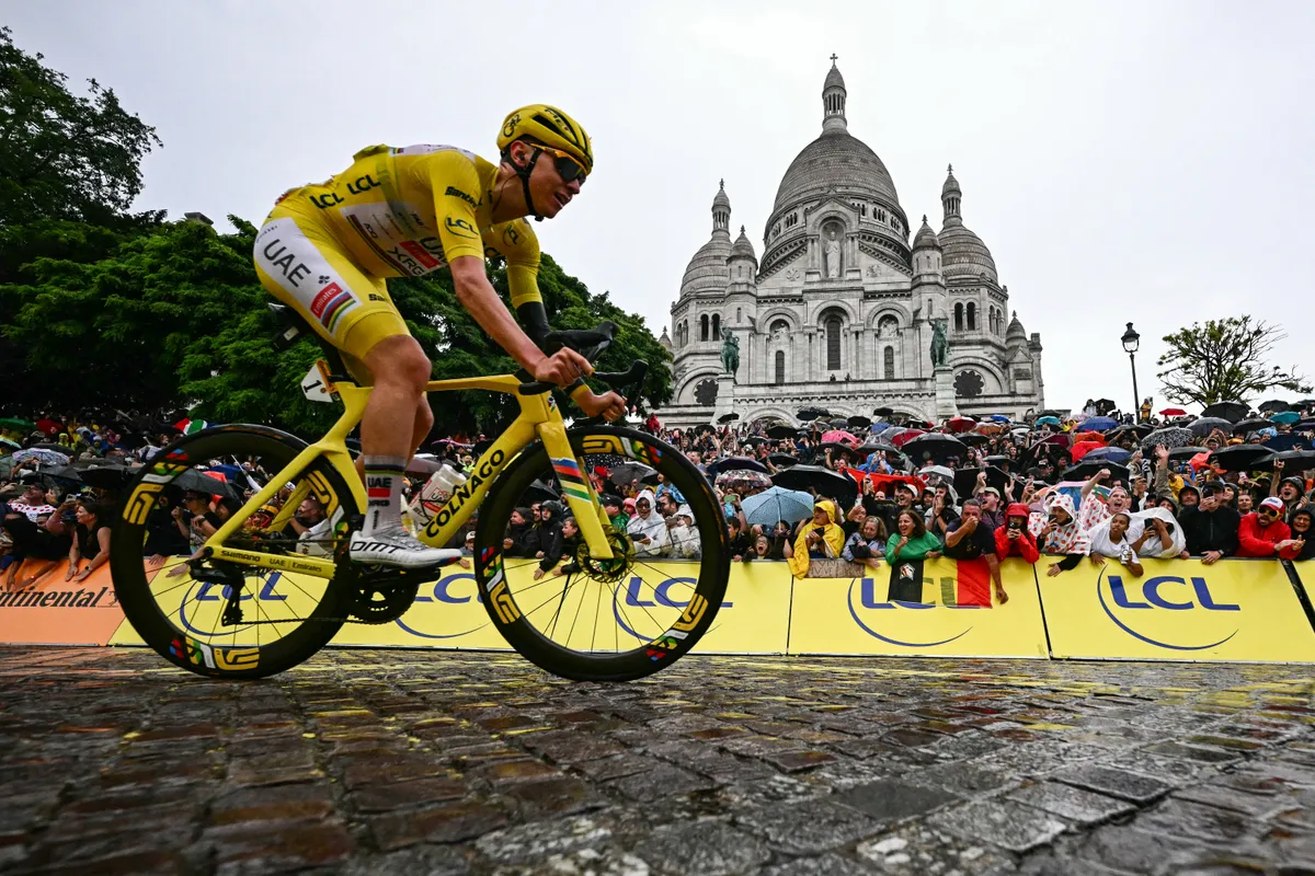 UAE Team Emirates - XRG team's Slovenian rider Tadej Pogacar wearing the overall leader's yellow jersey cycles past the Sacre-Coeur Basilica on the Butte de Montmartre during the 21st and final stage of the 112th edition of the Tour de France cycling race, 132.3 km between Mantes-la-Ville and Paris' Champs-Elysees Avenue, on July 27, 2025. (Photo by Loic VENANCE / AFP)