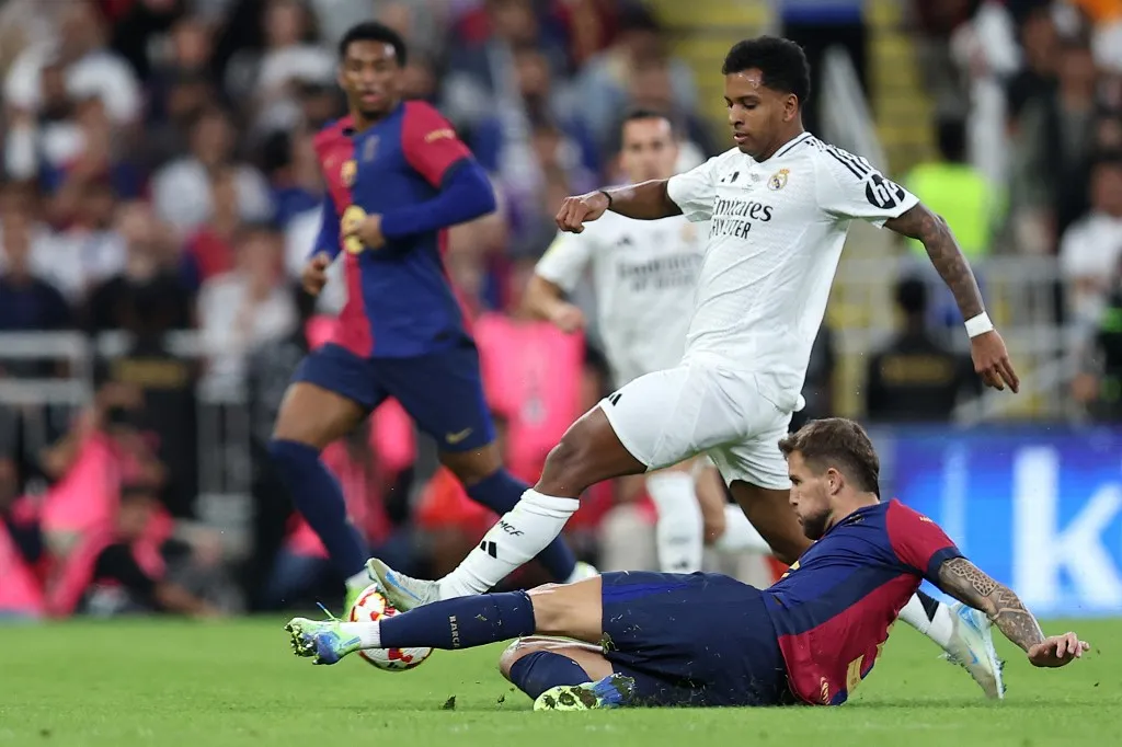 Real Madrid's Brazilian forward #11 Rodrygo runs with the ball past Barcelona's Spanish defender #5 Inigo Martinez Berridi during the Spanish Super Cup final football match between Real Madrid and Barcelona at the King Abdullah Sport City in Jeddah on January 12, 2025. (Photo by Haitham AL-SHUKAIRI / AFP)